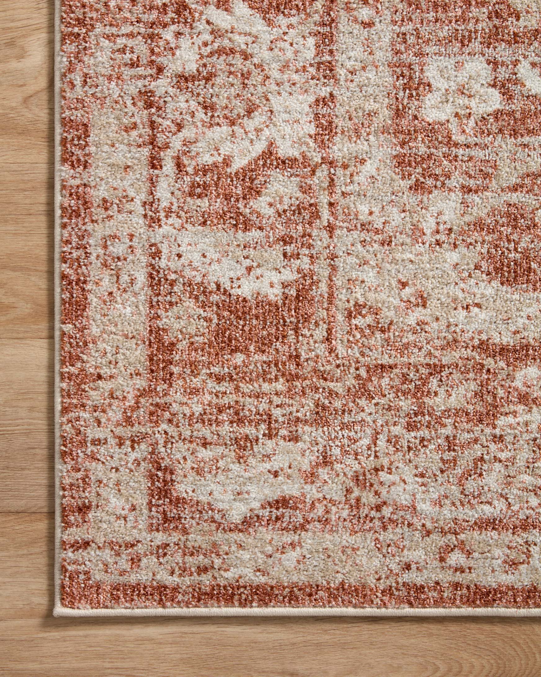 Rust and ivory distressed area rug with border on hardwood floor, flat texture.