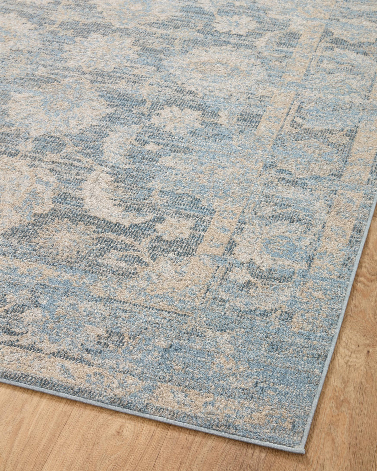 Blue and beige traditional area rug corner with distressed medallion pattern