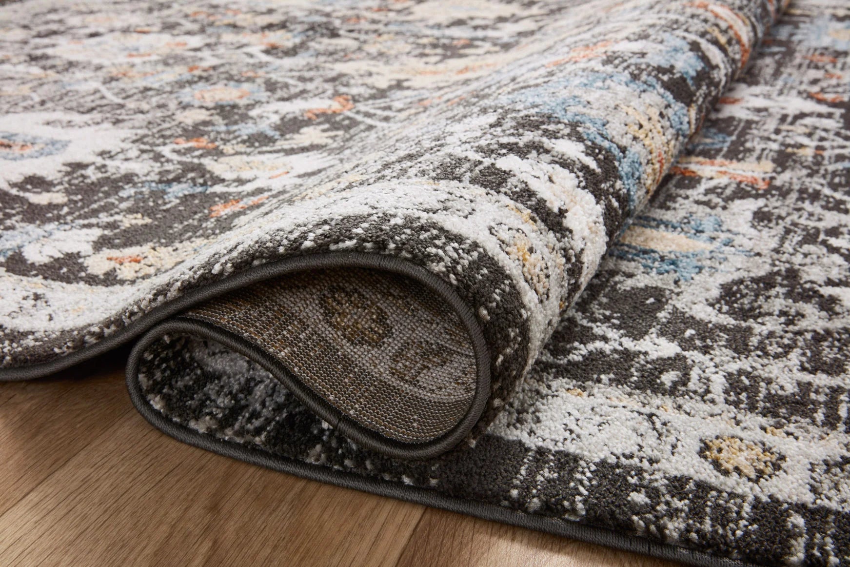 Charcoal round area rug edge with stitched border and layered distressed pattern detail