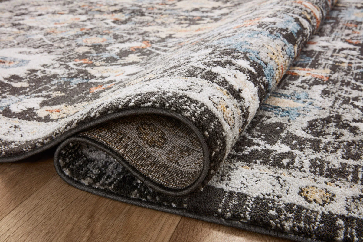 Charcoal traditional area rug corner with visible low pile and fringeless edge