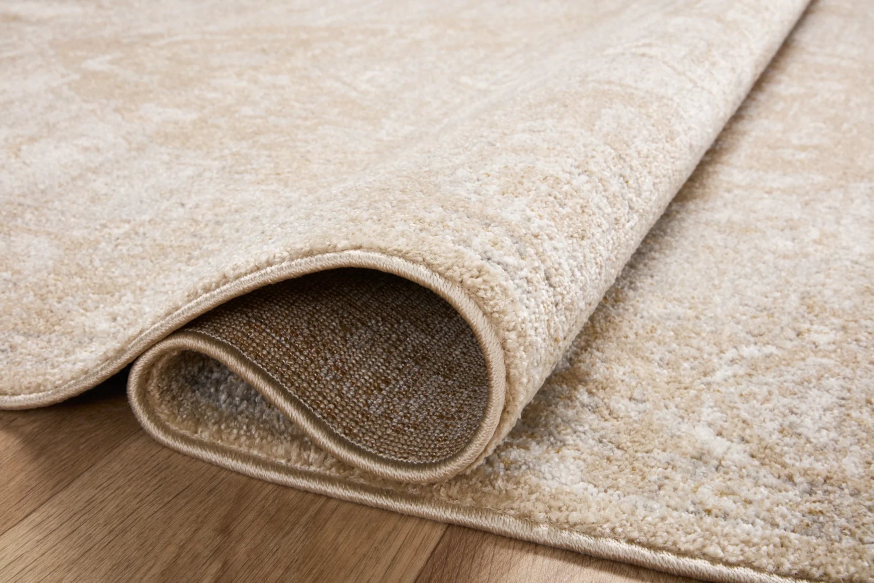 Beige runner rug with rolled edge and silver-brown reverse lining, close-up