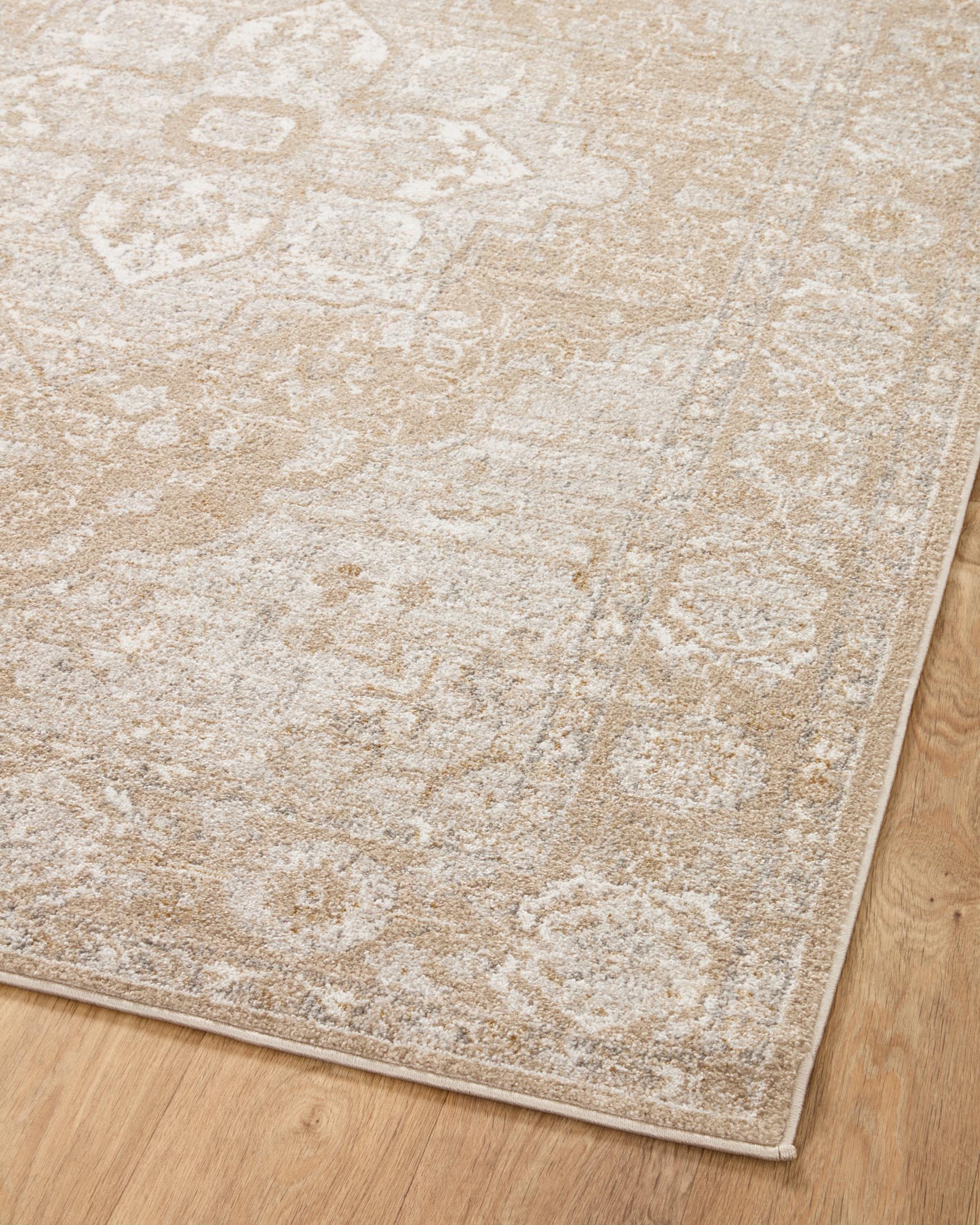 Beige and silver traditional area rug with ornate distressed pattern and low flat pile