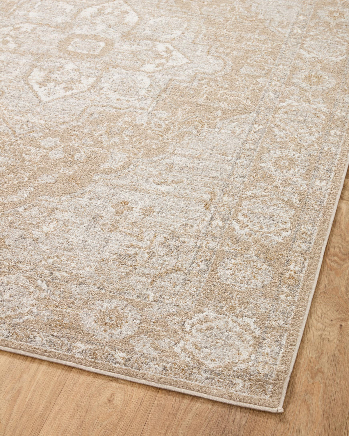 Beige and silver traditional accent rug surface with distressed pattern, close-up