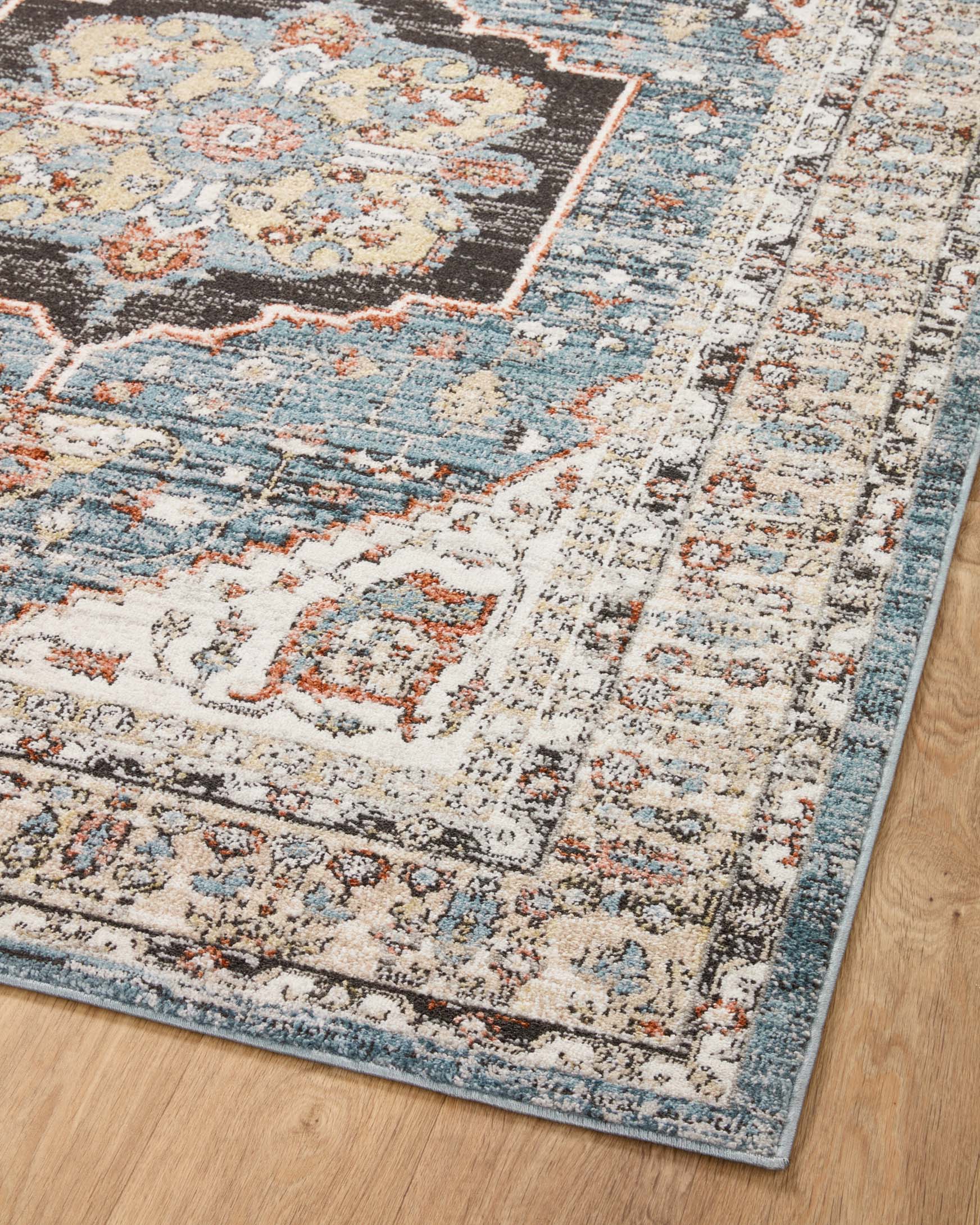 Traditional area rug top view with distressed sky blue, ivory, and rust geometric motifs