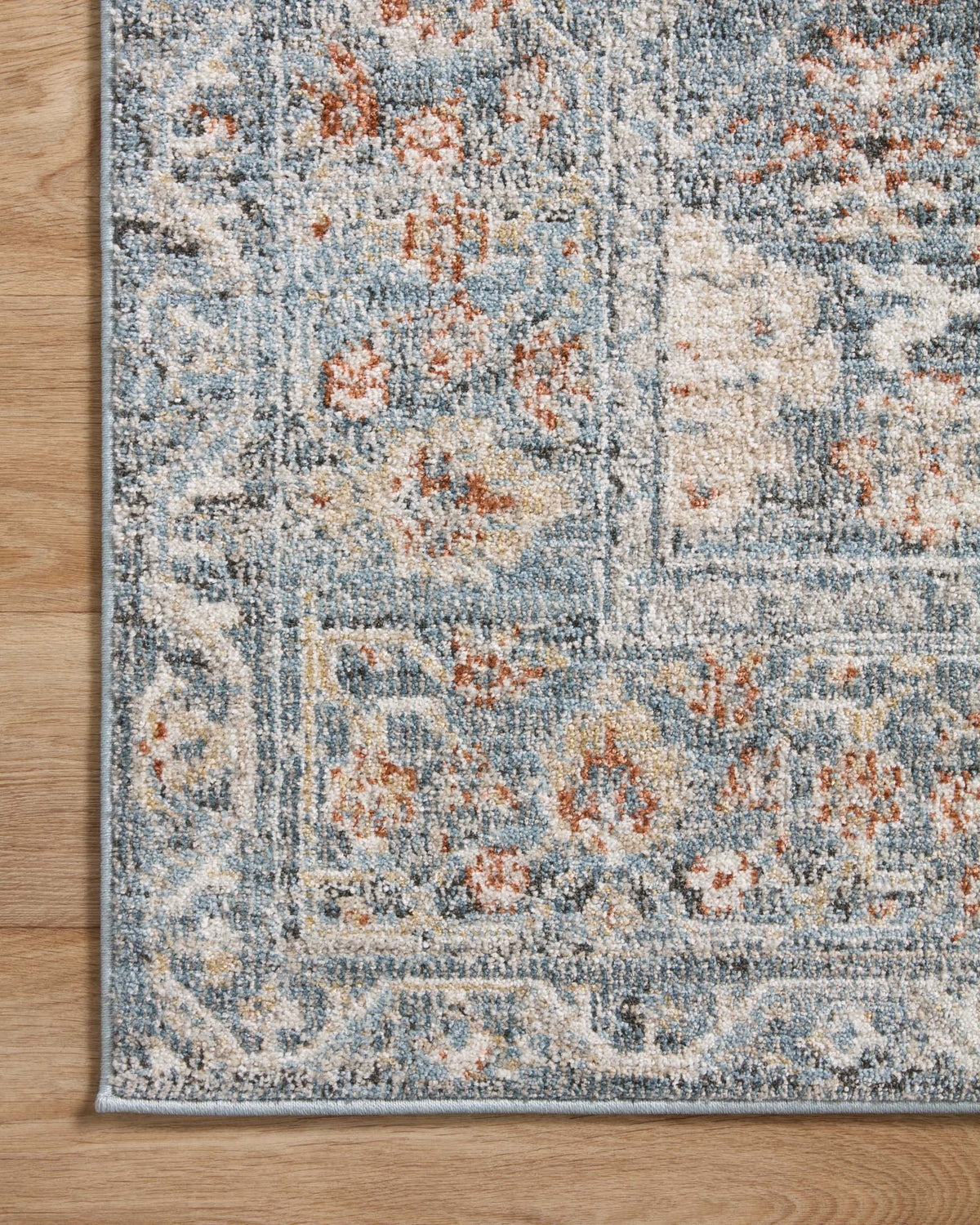 Traditional area rug border with sky-blue ornamental lines and rust-orange speckles