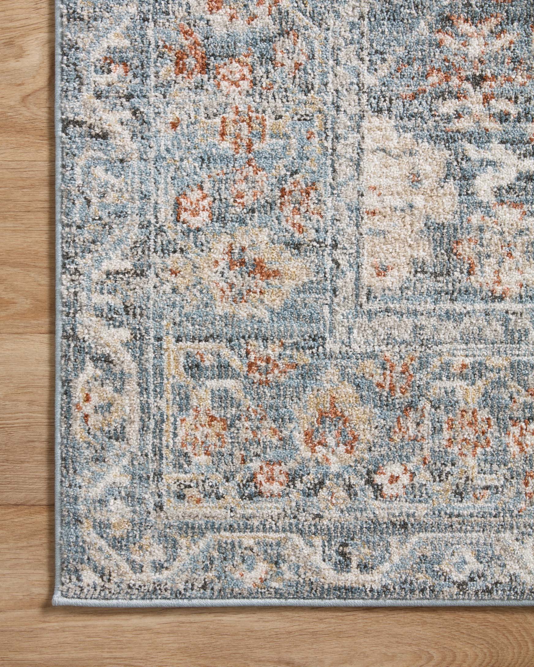 Traditional area rug close-up of sky blue pattern with rust-orange and beige distressed details