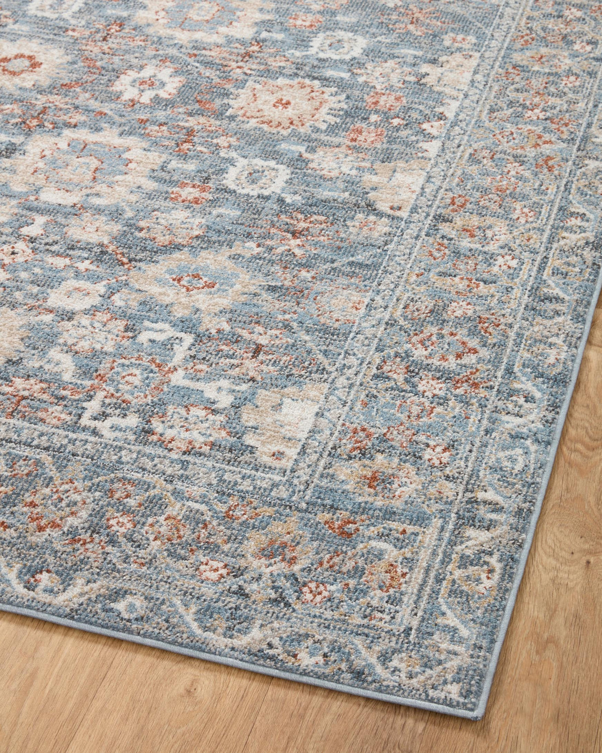 Round area rug with sky blue field and rust-orange accents, detailed ornate pattern