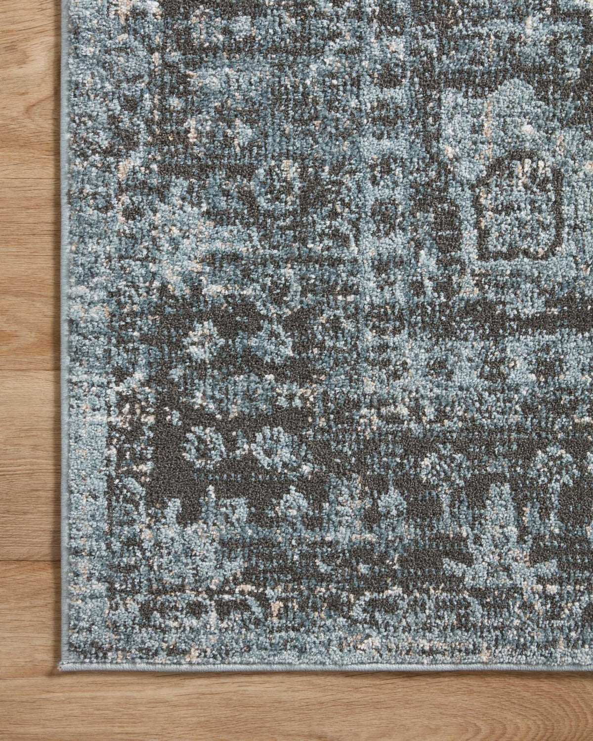 Sky-blue and charcoal traditional rug with distressed medallion-like center and border.
