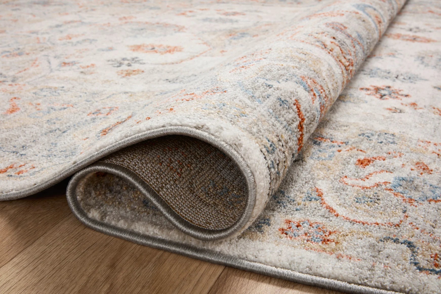 Ivory traditional area rug rolled edge showing textured pile and gray backing