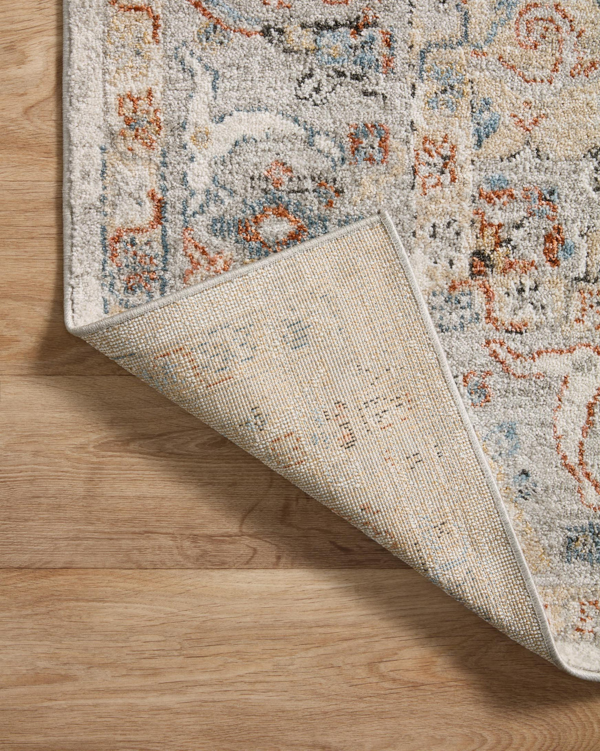 Ivory rug underside with woven texture and stitched edge, partially rolled