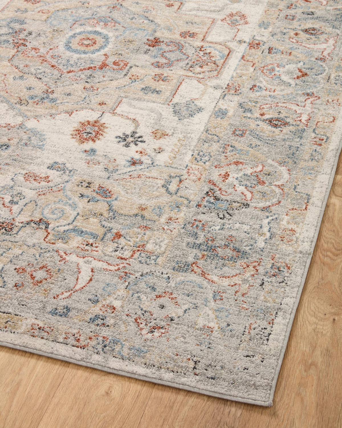 Ivory traditional area rug full view with distressed blue and orange scrolling motifs, flat border