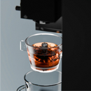 Transparent tea brewer cup with amber tea and open top, angled view