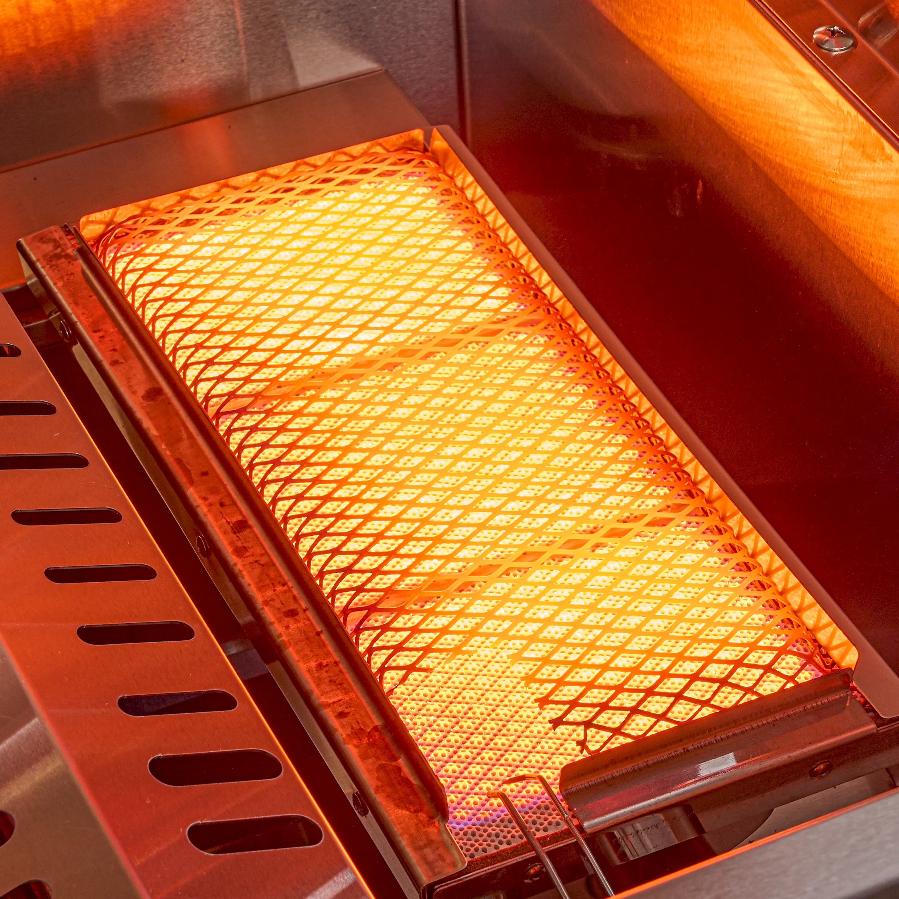 Close-up of glowing stainless infrared burner grid inside the BBQ grill