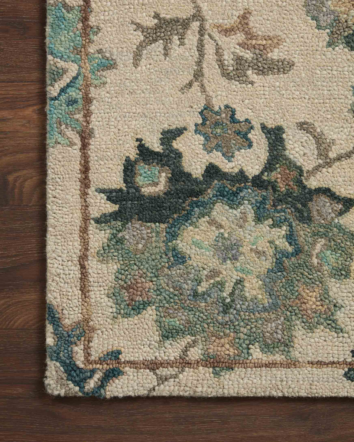 Cream area rug close-up with teal, blue, and brown floral pattern and textured pile