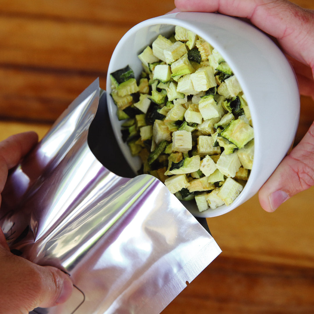 Hand pouring freeze-dried diced vegetables from a pouch into a bowl