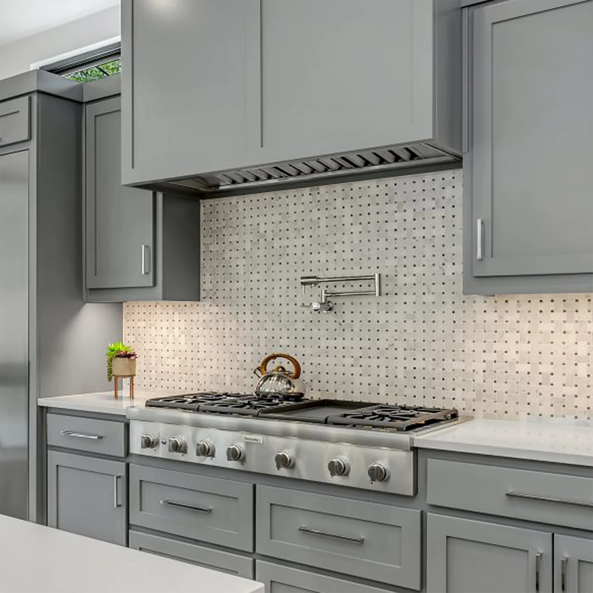 Stainless steel insert range hood over a gas cooktop with backsplash and mounting trim