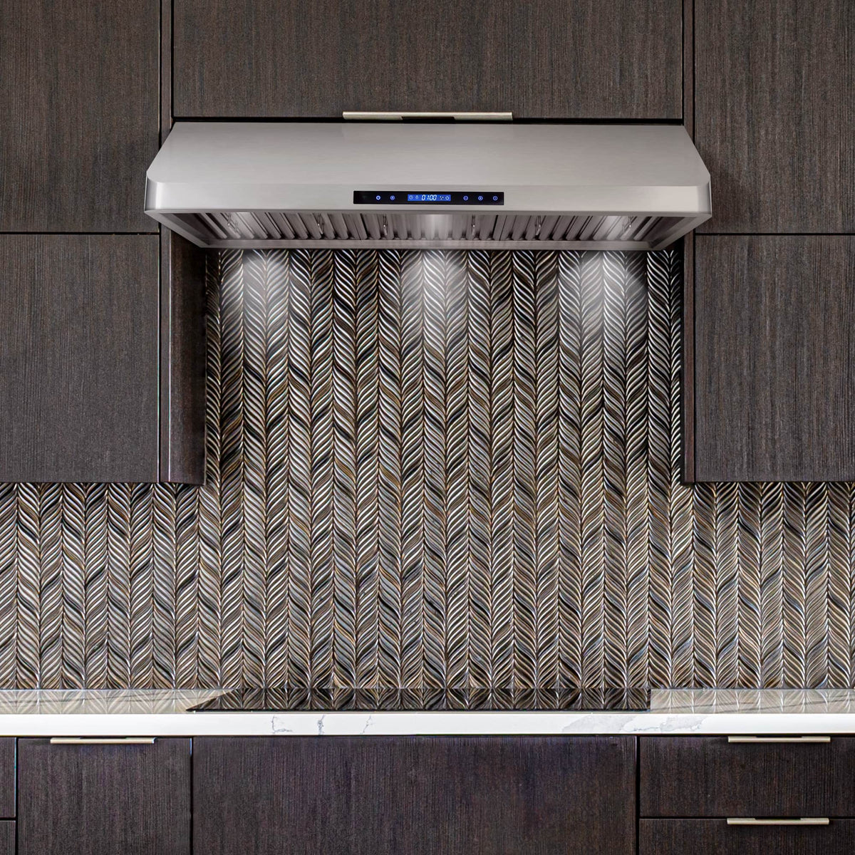 Stainless steel range hood with vent filters and backlit control panel above backsplash