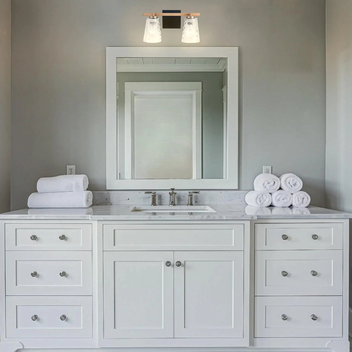 Two-light vanity fixture over a bathroom mirror with textured clear glass shades