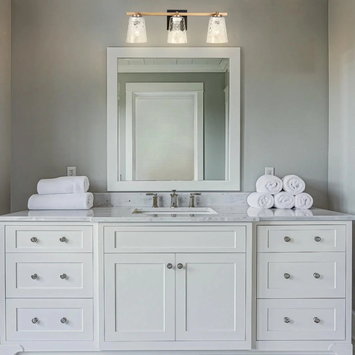 Three-light vanity light with clear textured glass shades and dark mounting bar
