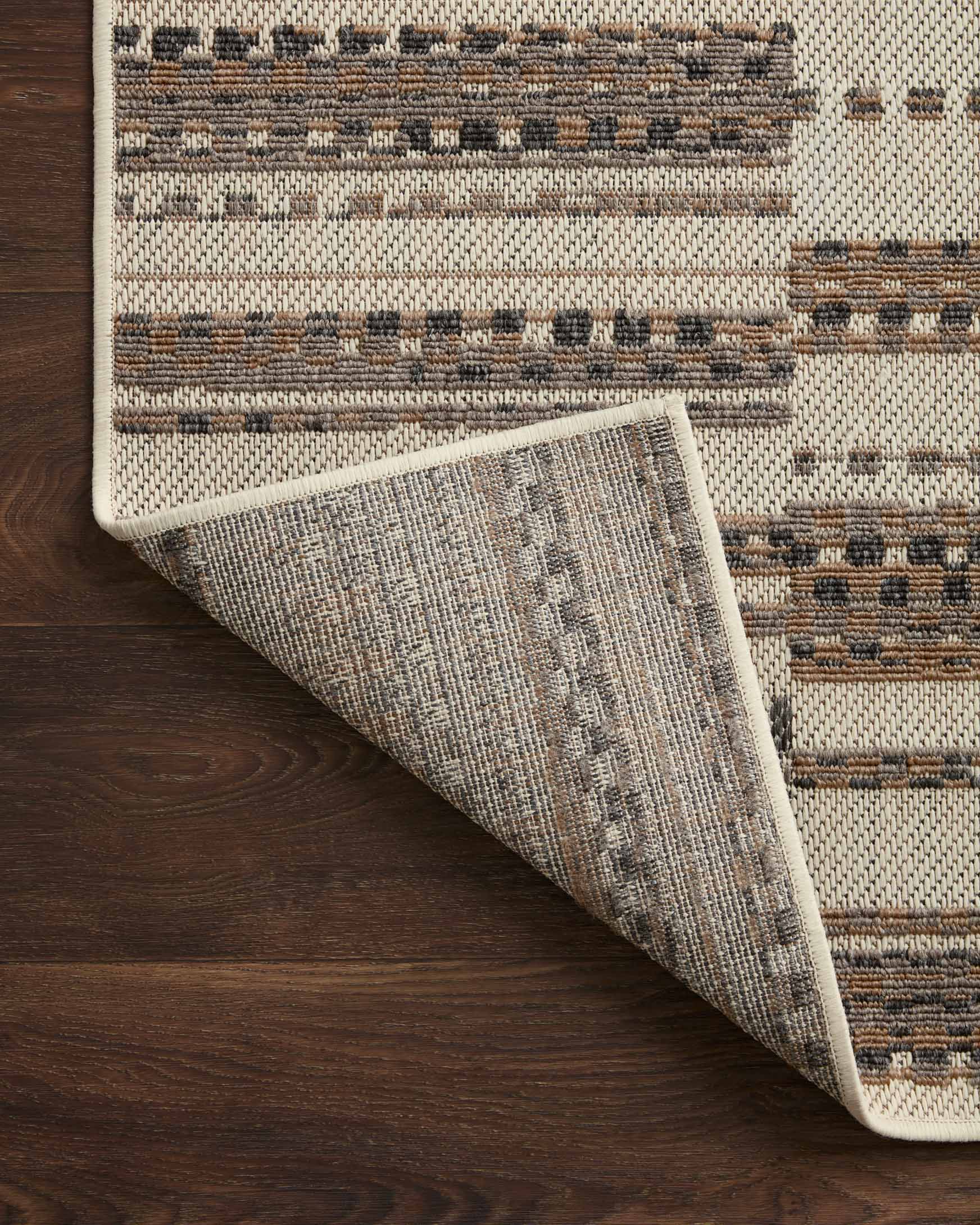 Ivory and taupe accent rug corner folded, showing textured weave and striped design.