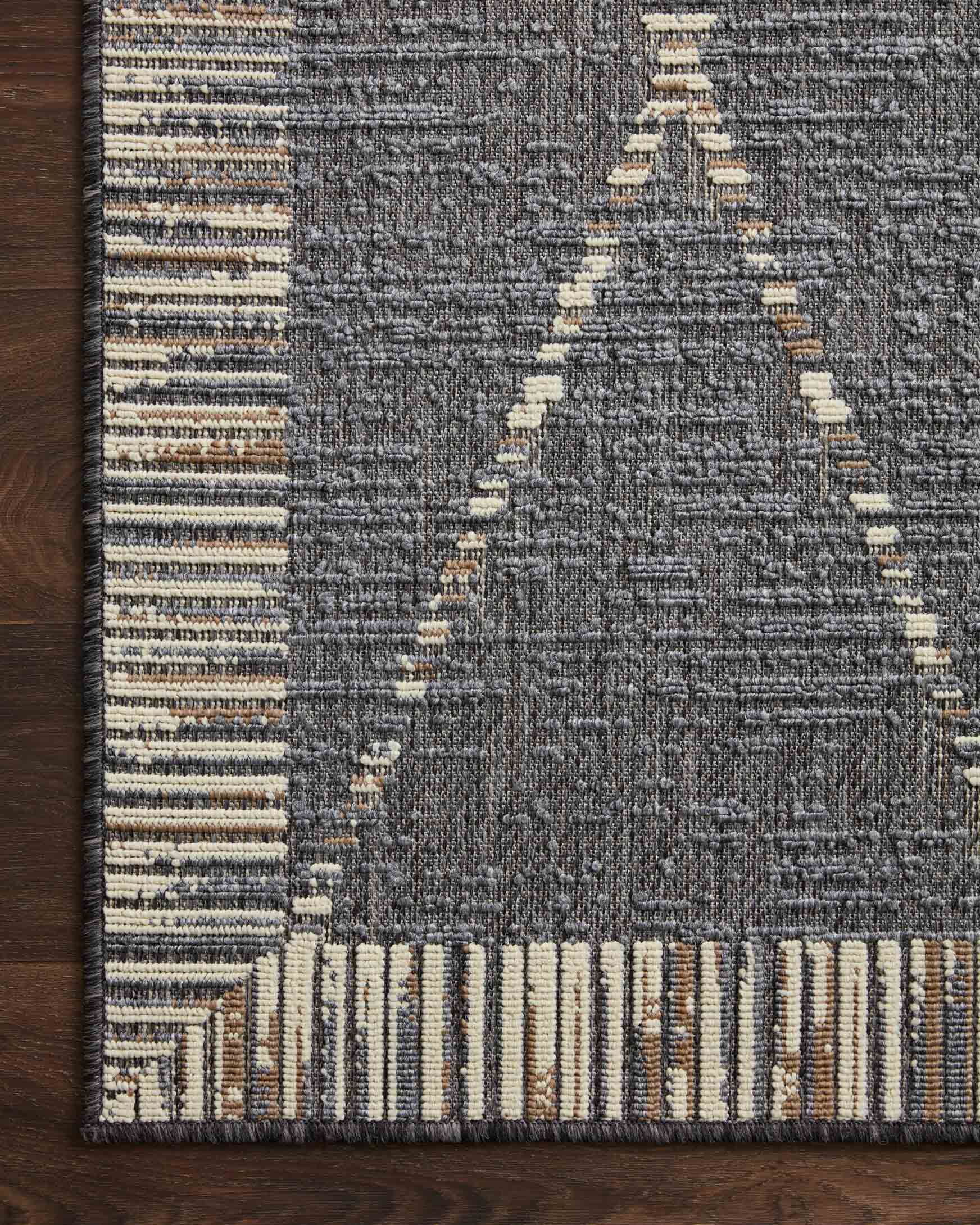 Slate gray rug corner with striped border, diamond lattice pattern, and flat weave