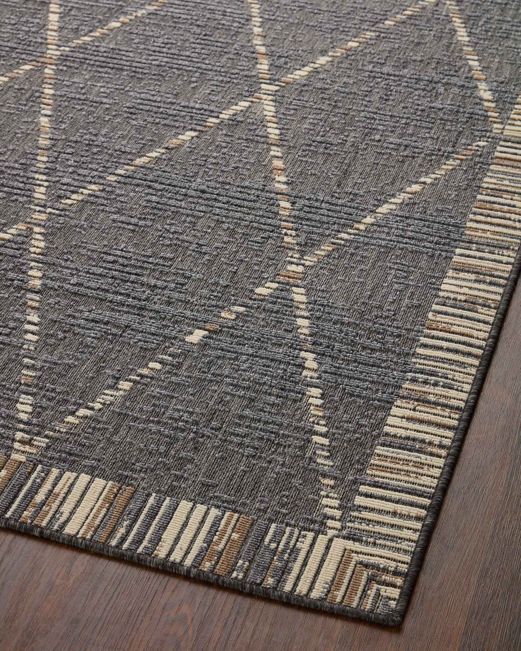 Slate gray area rug with diamond lattice design and beige striped band at edge