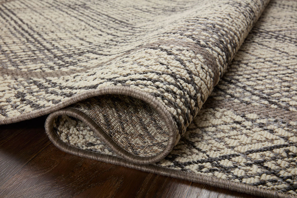 Close-up of indoor/outdoor accent rug showing ivory and charcoal textured weave and bound edge