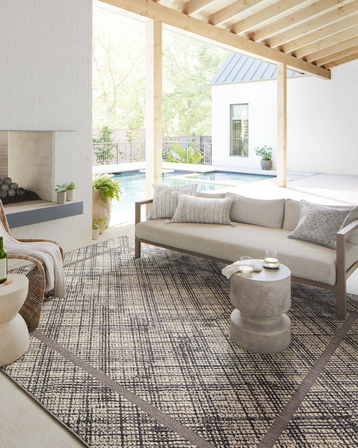 Ivory and charcoal indoor/outdoor area rug with geometric lattice design in a living room.