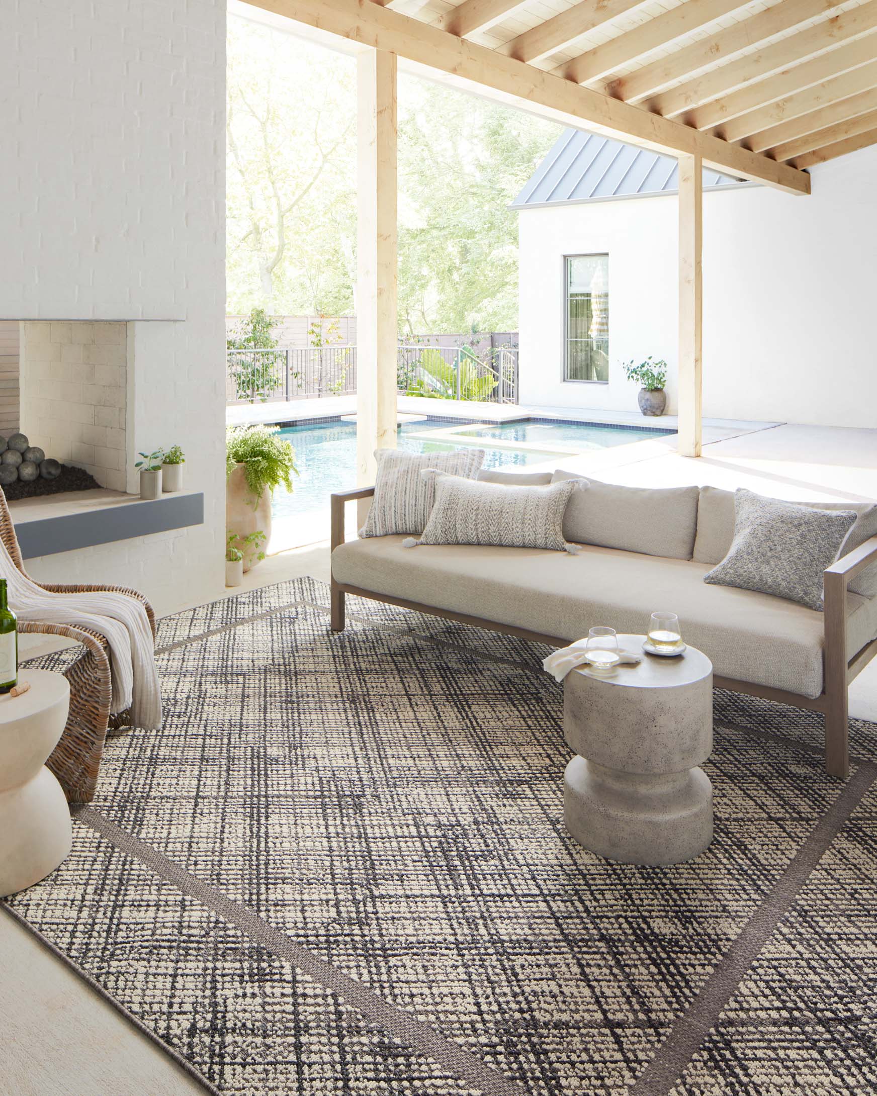 Loloi Rainier indoor/outdoor area rug in ivory and charcoal, geometric lattice pattern on floor