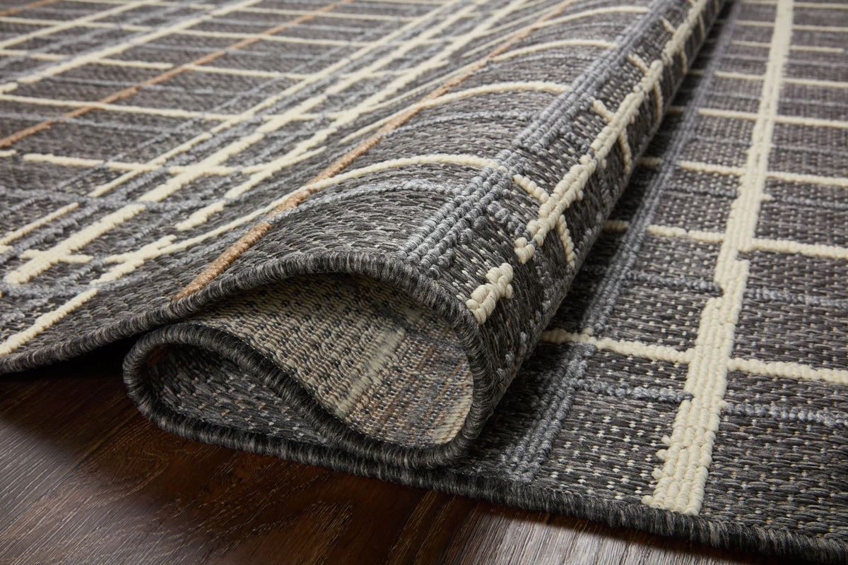 Charcoal area rug with ivory grid lines and tan accents, rolled edge close-up