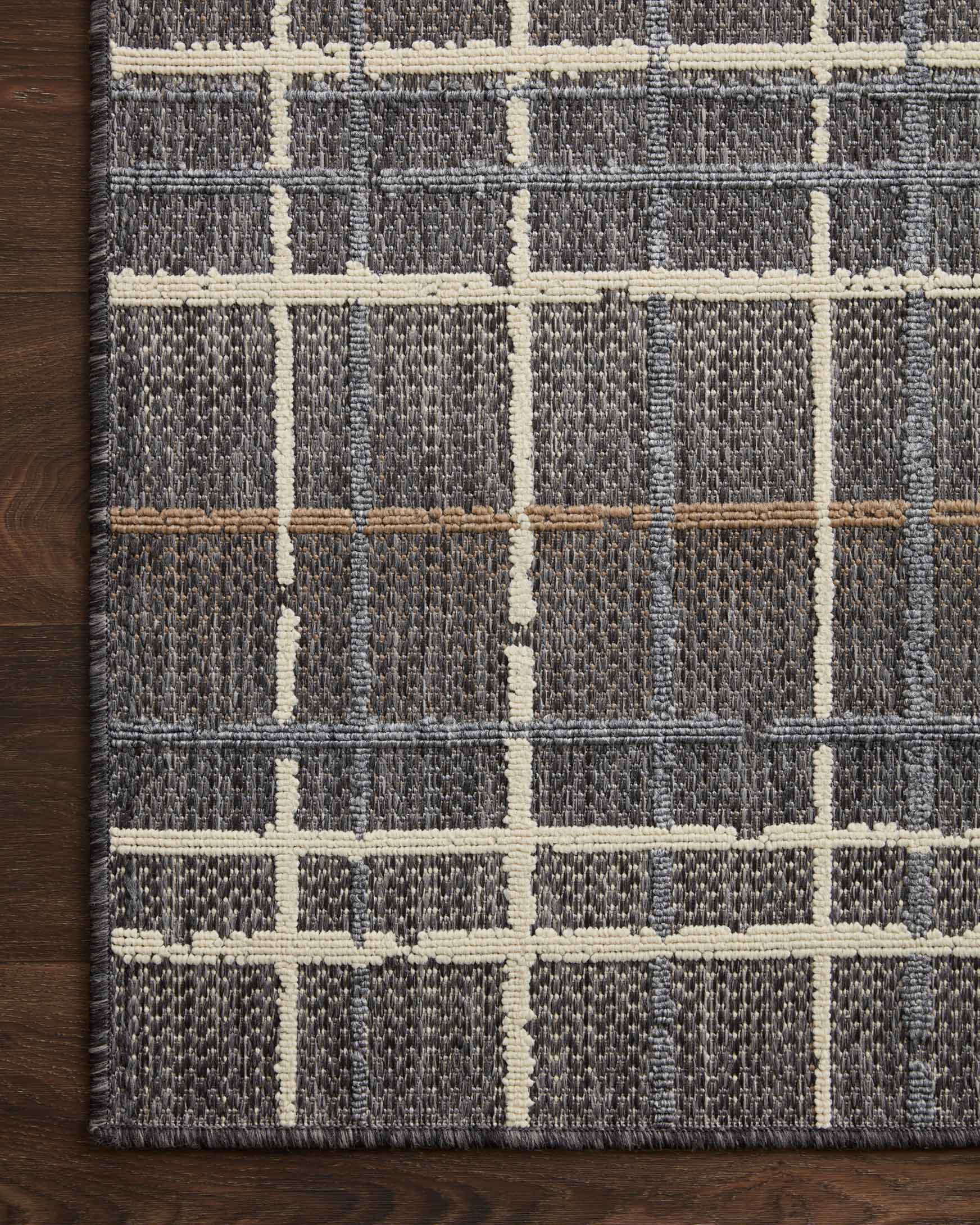 Close-up of charcoal rug with cream square grid pattern and flat woven surface.