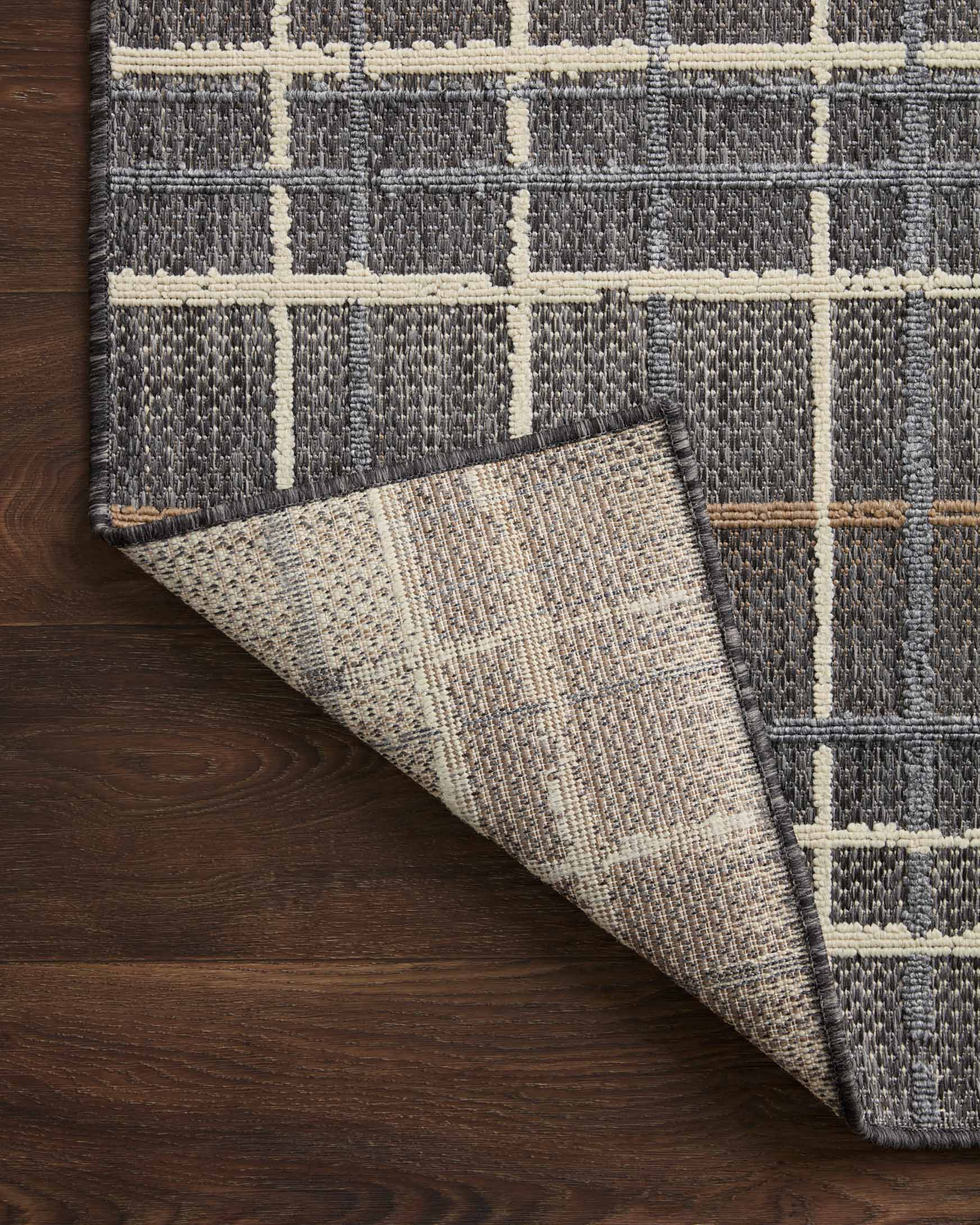 Charcoal runner rug corner with cream grid pattern and speckled textured fibers