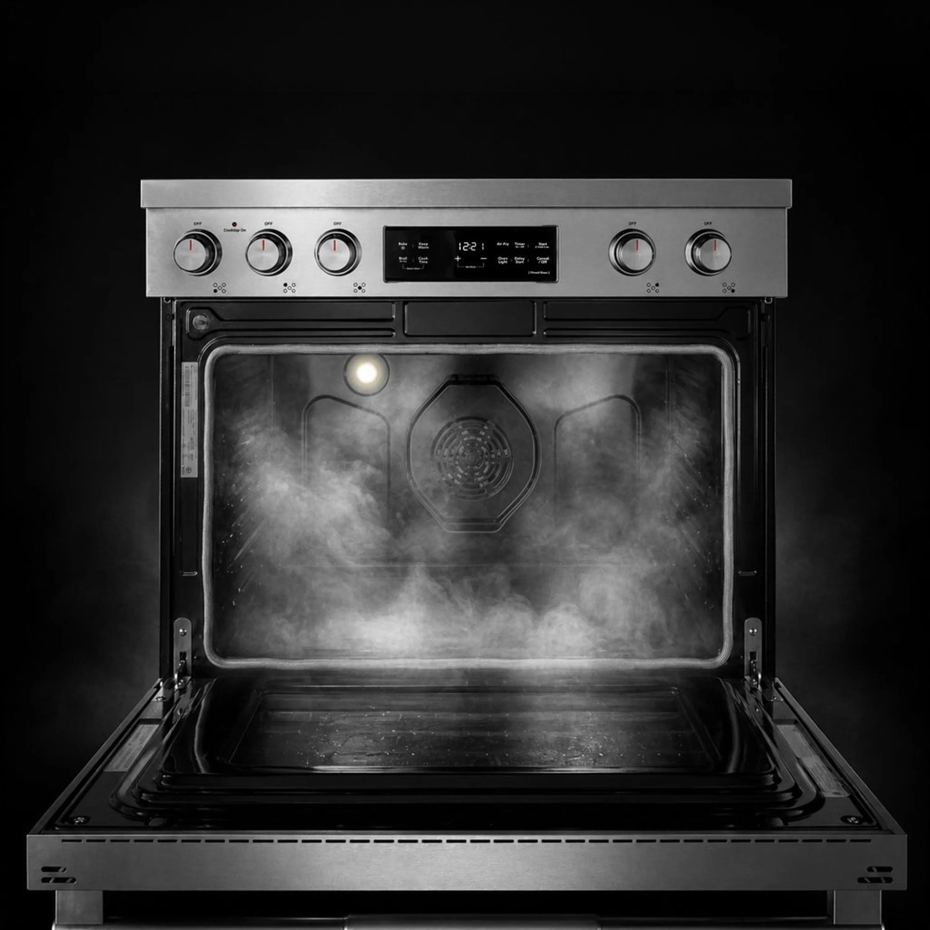 Electric range oven cavity with steam and glowing heating area behind open door