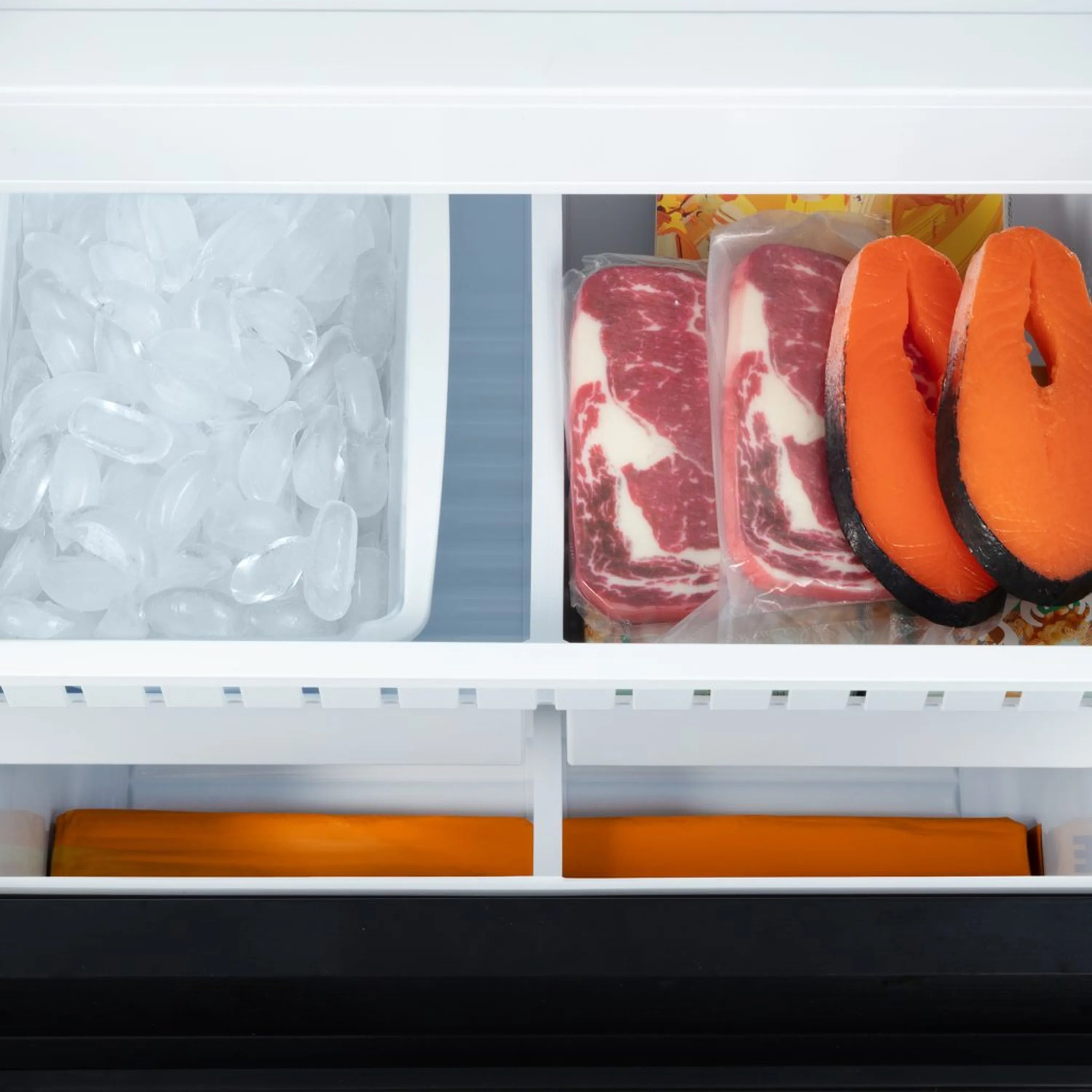 Refrigerator interior with glass shelves and clear ice bin on lower compartment