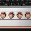 Rose gold control knobs on stainless steel gas range panel with small indicator marks