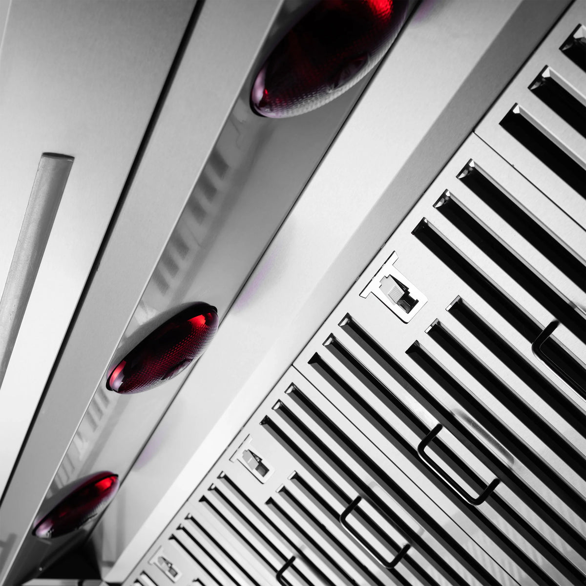 Close-up of stainless steel range hood baffle grille with red control lights