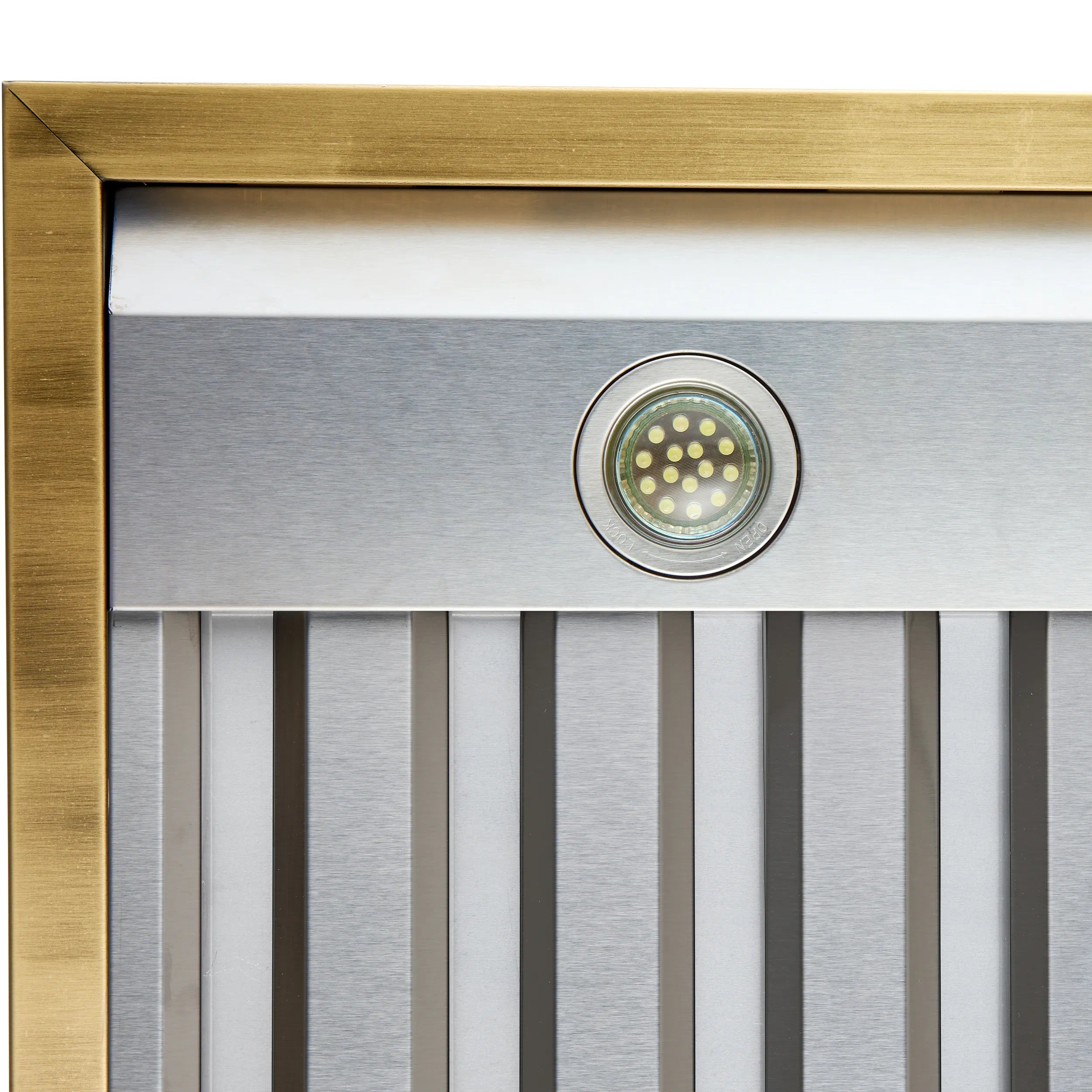 Range hood front light in circular bezel with antique brass border over silver vent slats
