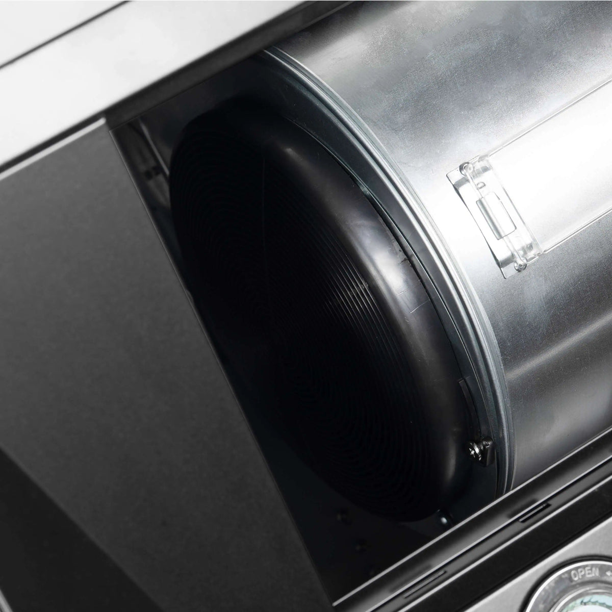 Black blower fan inside wall-mount range hood with vent duct opening.