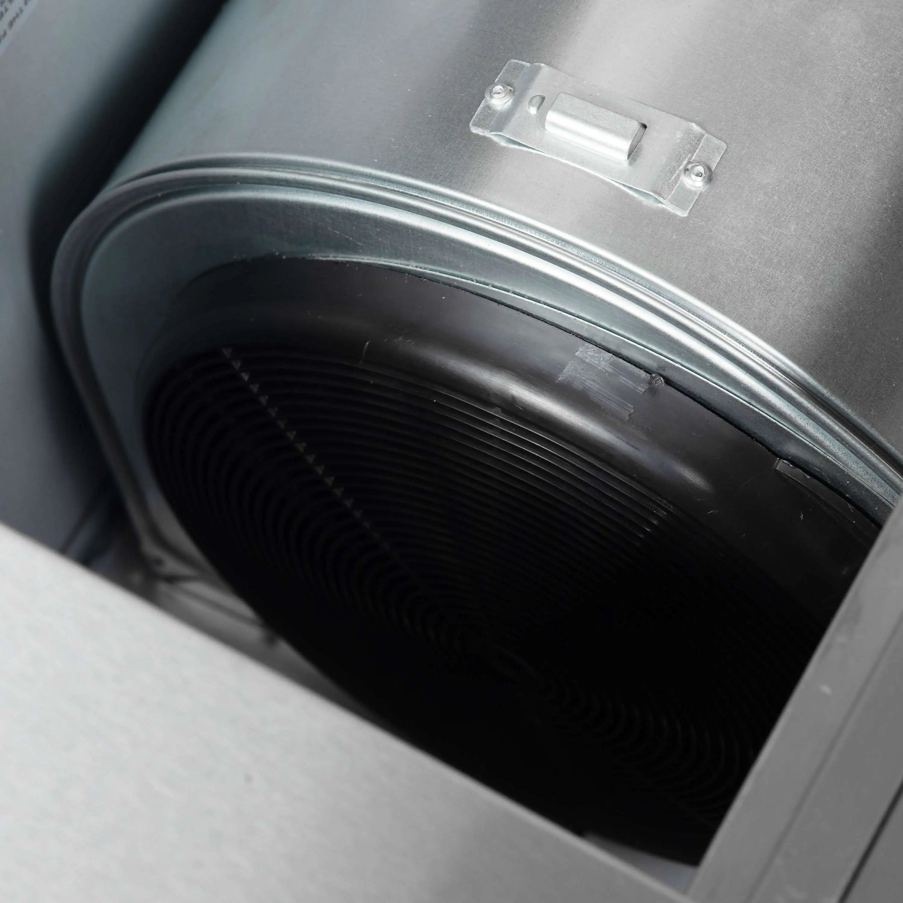Range hood duct blower opening with black flexible duct hose inside