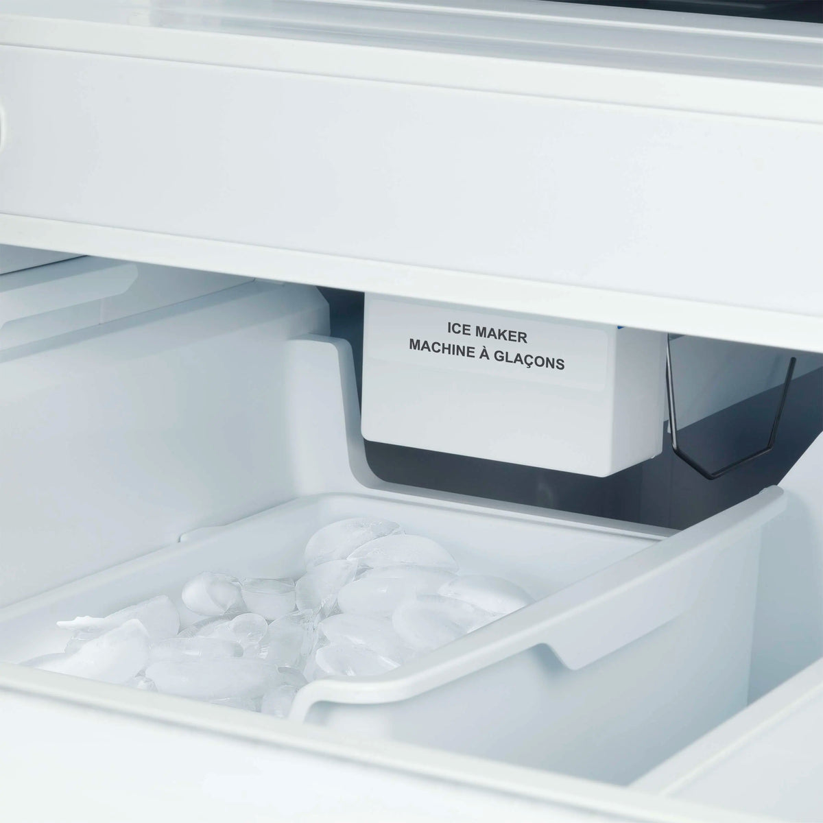 Freezer ice maker compartment with internal ice bin inside a stainless French door refrigerator