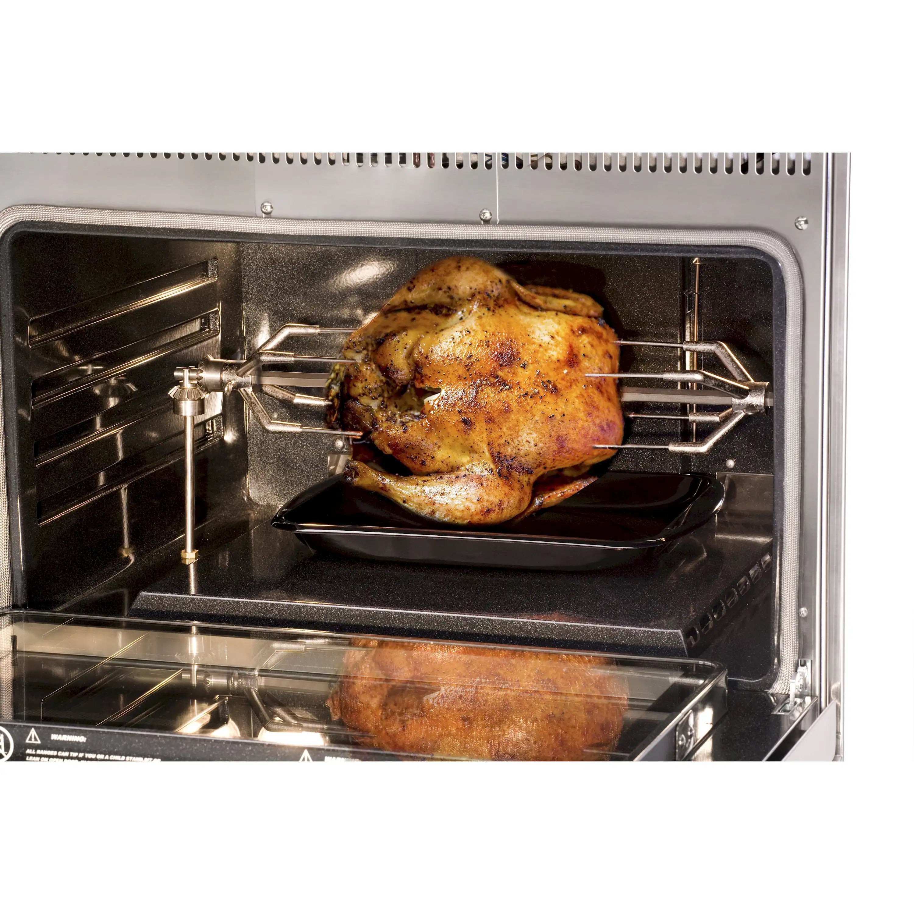 Rotisserie chicken inside stainless steel oven on a grill spit