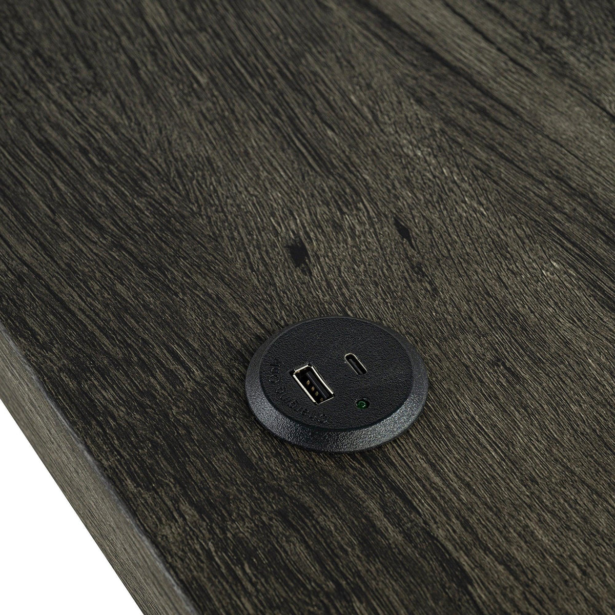Dark brown table top with round power outlet panel showing USB-A charging port