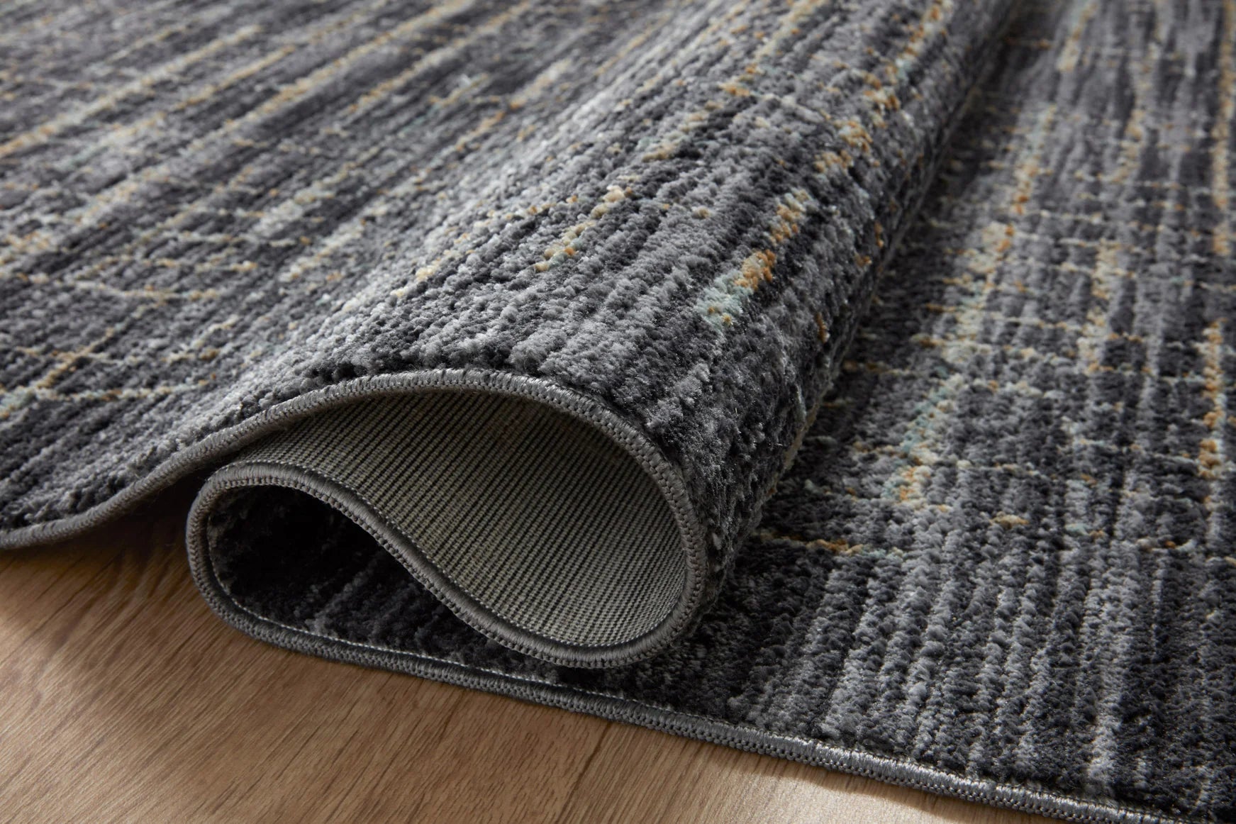 Rolled edge detail of dark runner rug with silver grid pattern and low pile