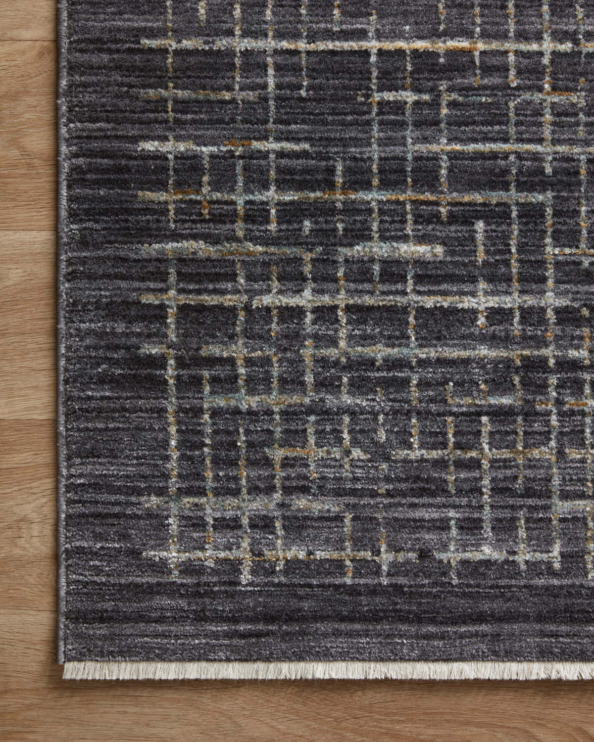 Charcoal area rug corner with silver grid lines and faint gold highlights