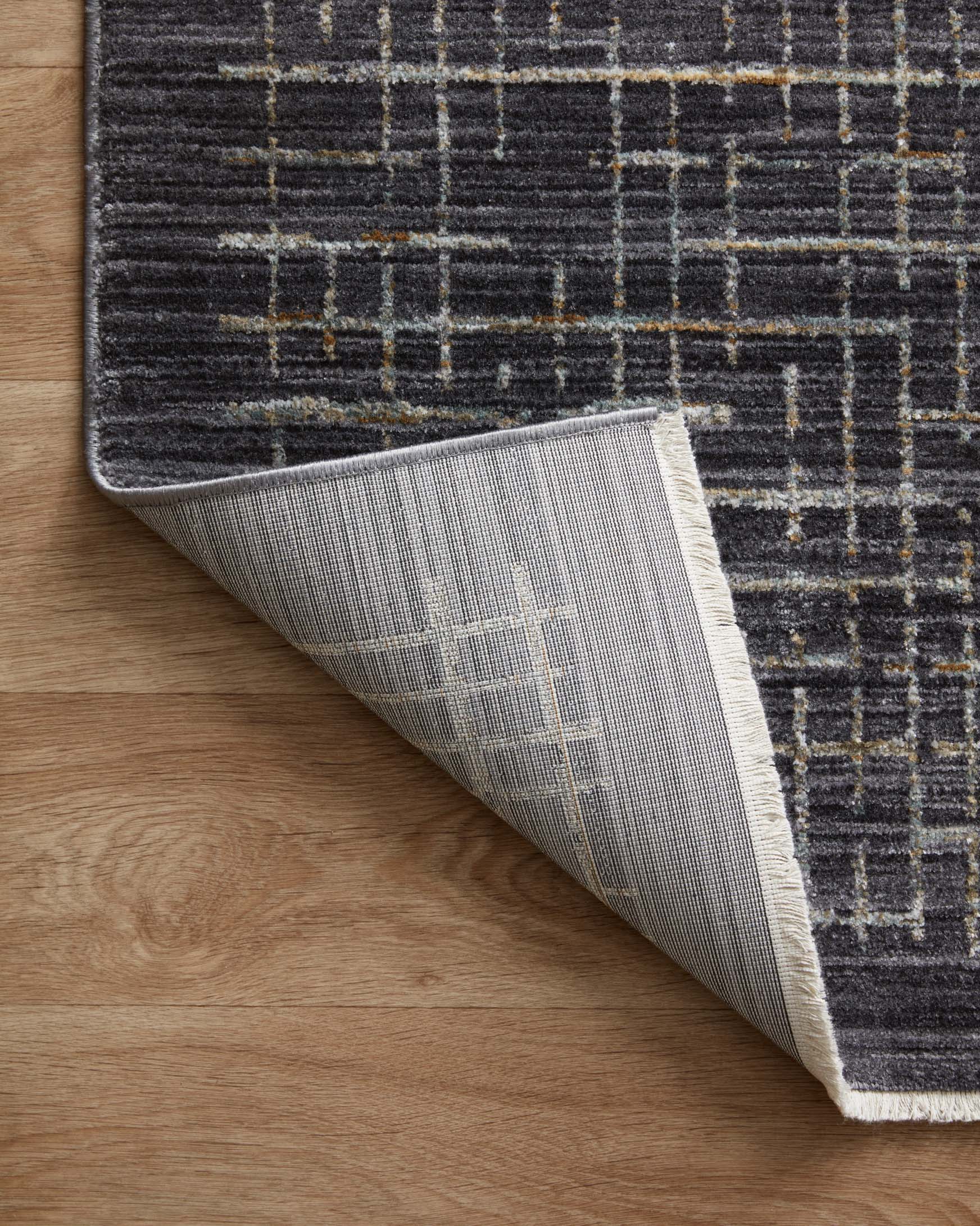 Dark gray rug with silver reverse fabric visible at lifted corner