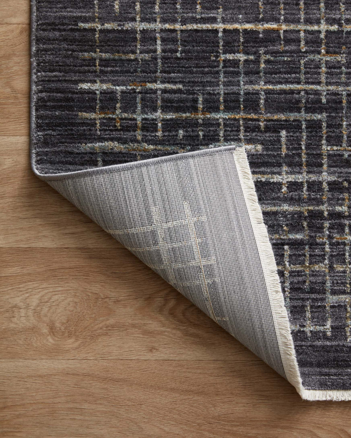 Runner rug with dark top and gray backing, rolled back to show thickness and weave