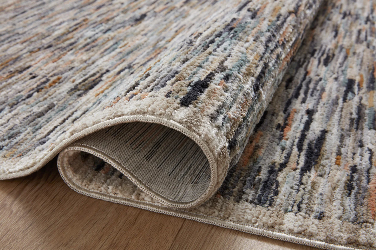 Rolled edge of multicolor runner rug showing light backing and stitched border