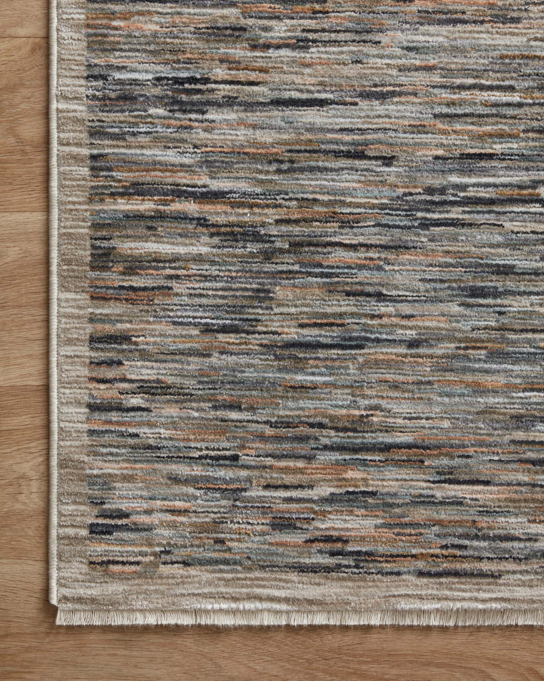 Edge view of contemporary area rug with fringe-like finish and speckled stripe pattern in beige and blue-gray