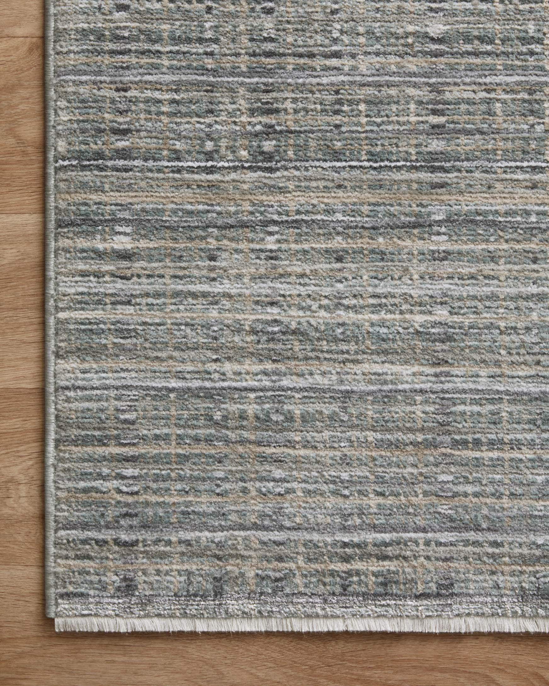 Corner view of gray and jade green runner rug with bordered edge and linear design.