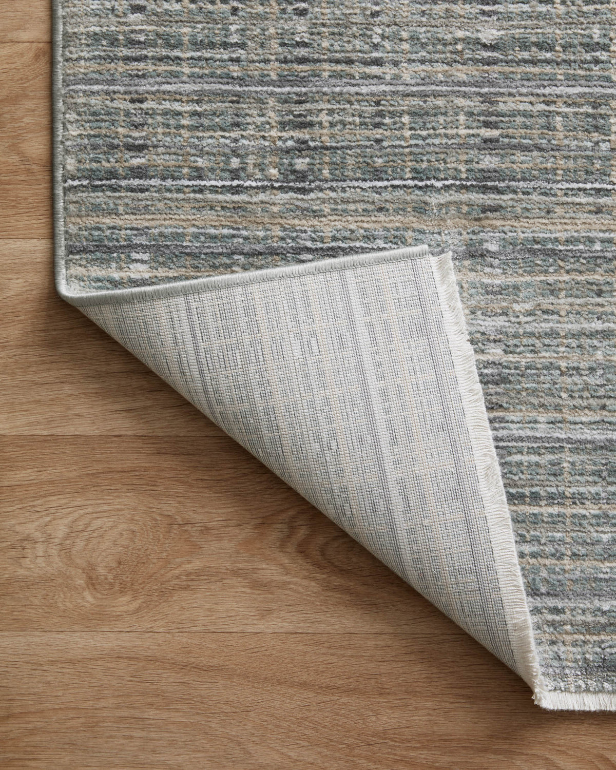 Gray-blue area rug with overlock edge and visible light gray backing at corner